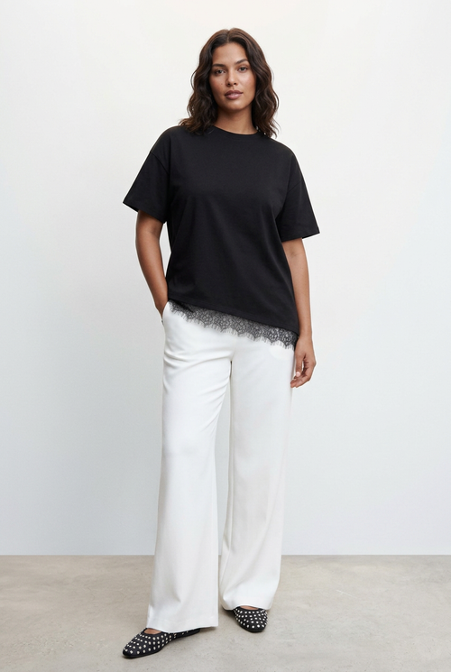 Modelo de pie con camiseta negra de encaje, sin texto